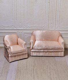 two chairs sitting next to each other on top of a wooden floor in front of a wall