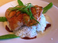 a white plate topped with rice and meat covered in sauce on top of green beans