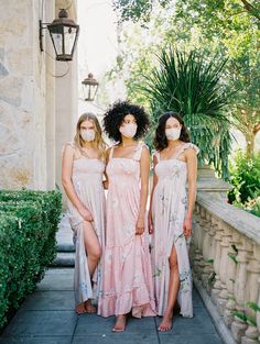 three women wearing face masks standing on a porch