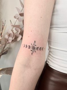 a woman with a tattoo on her arm that has phases of the moon in it