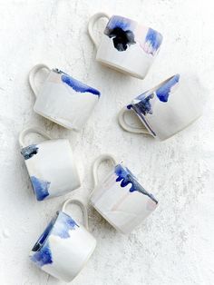 four white and blue coffee cups sitting next to each other on top of a table