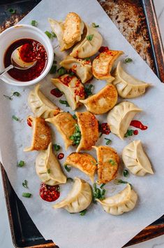 some dumplings are sitting on a tray with dipping sauce