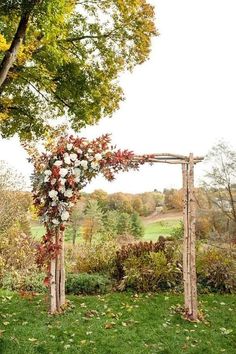 an outdoor wedding ceremony setup with flowers on the arch and greenery in the background