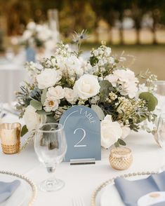 the table is set with silverware and white flowers