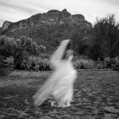 a woman is running in the grass with mountains in the backgrounds