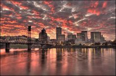 the city skyline is reflected in the water at sunset, with pink and orange clouds