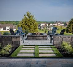 an outdoor patio with chairs and fire pit in the center, grass on the ground