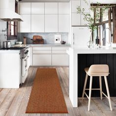 a kitchen with white cabinets and wood flooring next to a counter top oven, stools and an area rug