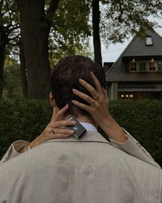 a woman covering her face with her hand while talking on a cell phone in front of a house