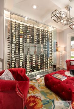 a living room filled with lots of red furniture and bottles of wine on the wall