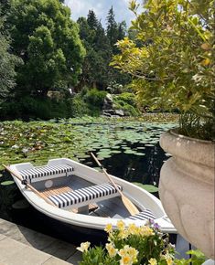 a small boat sitting on top of a lake filled with water lillies and greenery