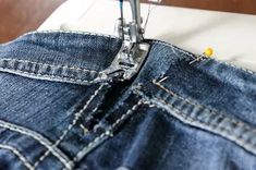 the sewing machine is working on some jeans