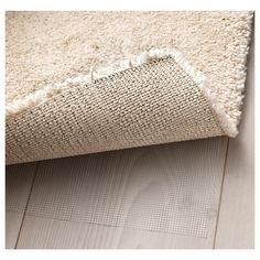 a white rug on top of a wooden floor next to a beige rug with fringes