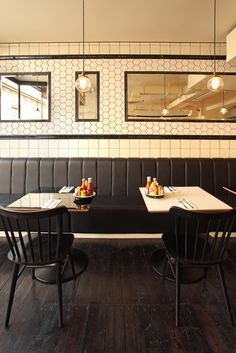 a restaurant with black leather booths and white tiled walls, along with wooden flooring