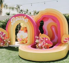 an inflatable rainbow themed birthday party with balloons and flowers on the lawn at a children's birthday party