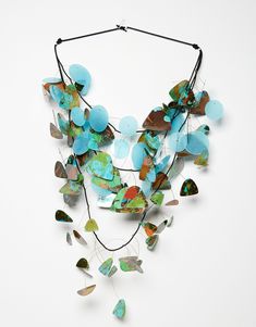 a necklace with blue and green beads hanging from it's side on a white surface