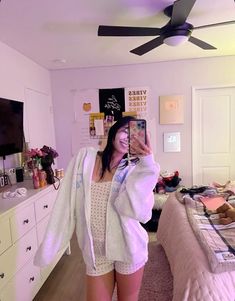 a woman is taking a selfie in her bedroom while wearing a robe and shorts