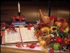 an open book sitting on top of a table filled with autumn leaves and pumpkins