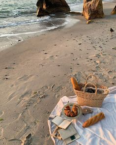 bread and pastries sit on a towel at the beach near some large rock formations