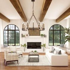 a living room filled with white furniture and lots of wooden beams on the ceiling, along with large windows