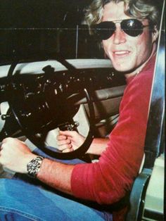 a man sitting in the drivers seat of a car with his hands on the steering wheel