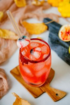 a red drink sitting on top of a wooden cutting board