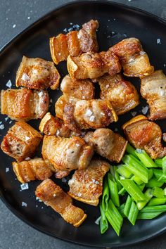 a black plate topped with meat and green beans