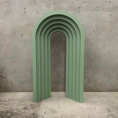 an arch shaped sculpture in front of a concrete wall with cement floor and walls behind it