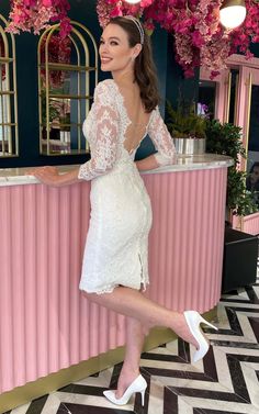 a woman posing in front of a pink bar with flowers hanging from it's ceiling