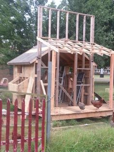 a chicken coop built into the side of a house with chickens in it's yard