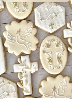 decorated cookies with white frosting and gold decorations on a wooden surface, including a cross