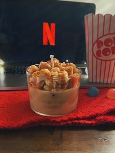 a bowl of food sitting on top of a table next to a cup of popcorn