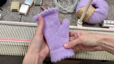 a person is holding a purple mitt in front of some yarns and scissors