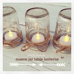 three mason jar candles tied with twine on a white wooden tablecloth and text overlay that says simply decorated mason jar table lanterns