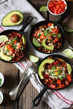 three skillets filled with food sitting on top of a wooden table next to bowls of salsa