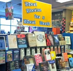 there are many books on display in the store and one has a sign that says short stories for a month