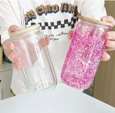 a person holding a pink glitter tumbler next to a plastic cup