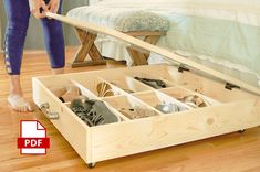 a person standing next to a bed with shoes in the bottom drawer and underneath it