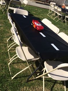 a table with cars on it in the middle of some chairs and tables set up for an event