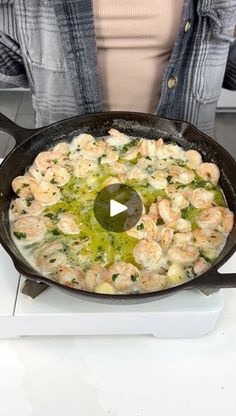 a woman cooking shrimp in a skillet on the stove