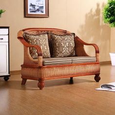 a wicker couch sitting on top of a hard wood floor next to a potted plant