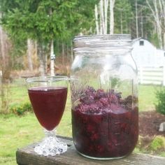 a mason jar filled with liquid next to a glass full of berry compote