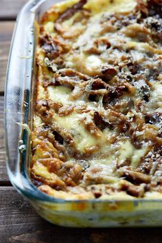 a casserole dish with meat and cheese in it sitting on a wooden table