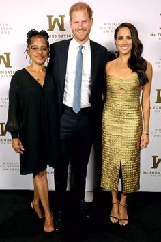 two women and a man standing next to each other in front of a black carpet