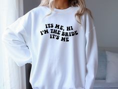 a woman wearing a white sweatshirt that says it's me, i'm the bride