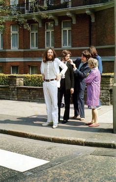 some people are standing on the side walk talking to each other and one is wearing a white suit