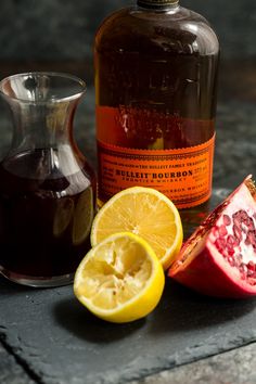 pomegranate, lemon and honey sit next to a bottle of syrup