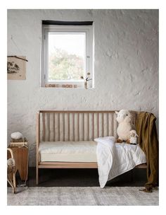 a teddy bear sitting on top of a wooden bench in front of a white wall