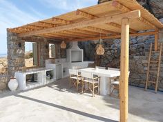 an outdoor kitchen and dining area with stone walls