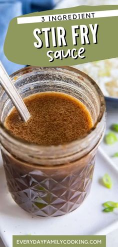 a jar filled with stir fry sauce sitting on top of a white plate next to a spoon